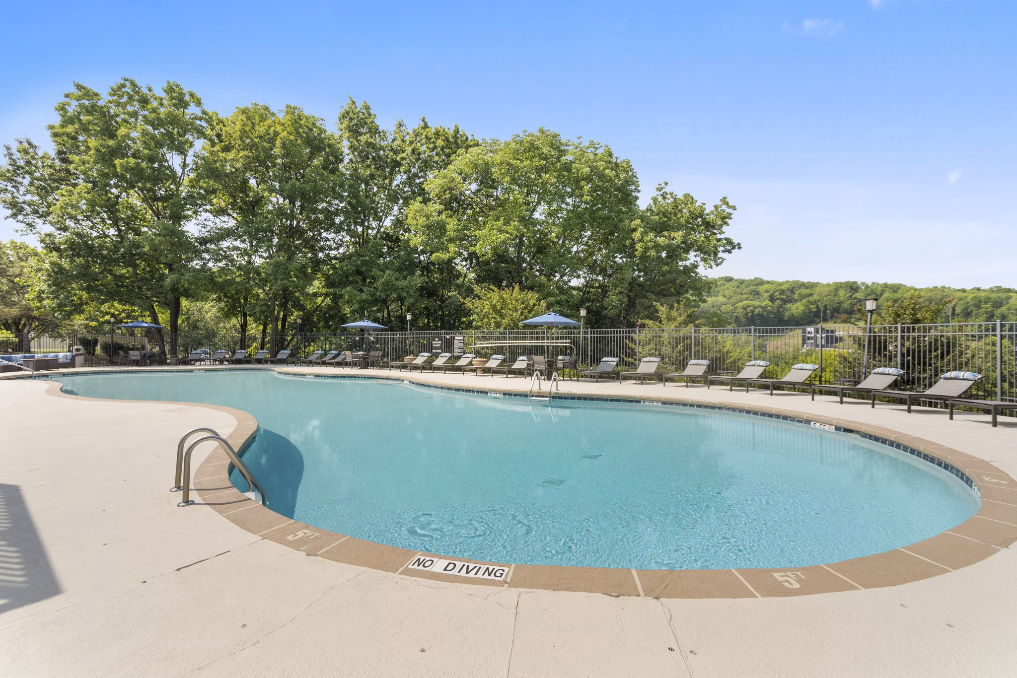 Resort-style pool with lounge chairs at Brentwood Oaks Apartments, offering a luxury living experience in a serene environment