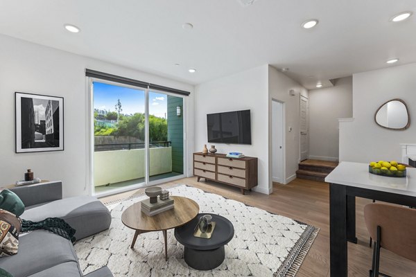 Living room with modern decor and large windows at Ascent at Campus of Life Apartments