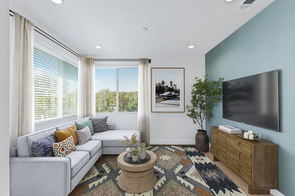 Living room with modern furnishings and large windows at Ascent at Campus of Life Phase II Apartments