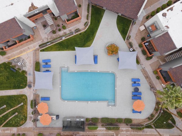 Resort-style pool with shaded lounge areas at Sierra Pines Apartments, offering luxury living in a serene setting