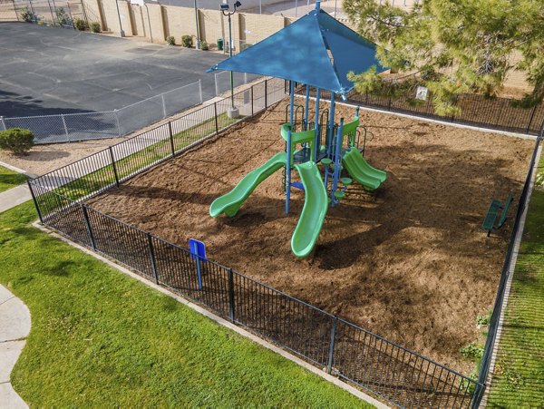 Playground surrounded by lush greenery at Sierra Pines Apartments, offering recreational space for families and children