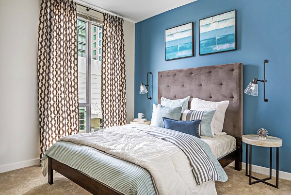 Modern bedroom with chic furnishings at Flats on D Apartments, featuring cozy bedding and stylish decor