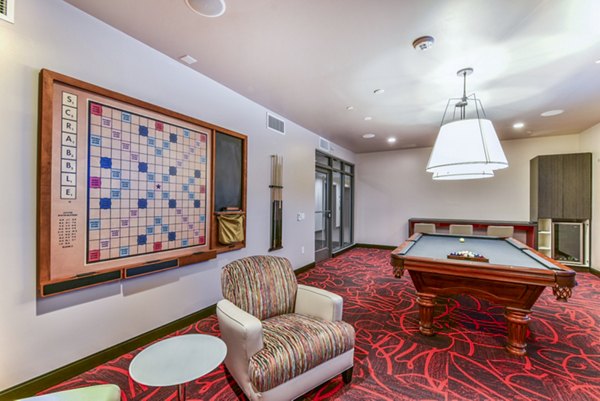 Vibrant clubhouse game room with pool table and lounge area at Flats on D Apartments
