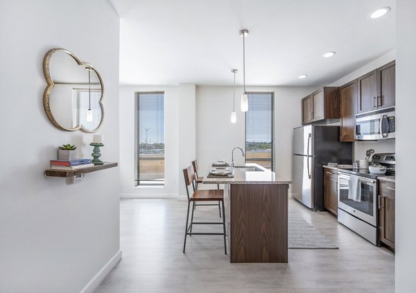 Modern kitchen with stainless steel appliances and granite countertops in Flats on D Apartments