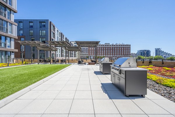Outdoor grill area at Flats on D Apartments: Modern patio with seating for gatherings
