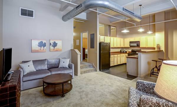 Spacious living room with modern design at Heinz Lofts Apartments, featuring sleek furniture and abundant natural light