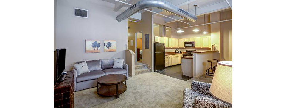 Spacious living room with modern design at Heinz Lofts Apartments, featuring sleek furniture and abundant natural light