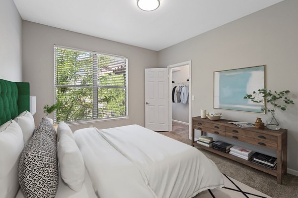 Cozy bedroom with modern decor at Cyan at Green Valley Apartments, featuring plush bedding and ample natural light