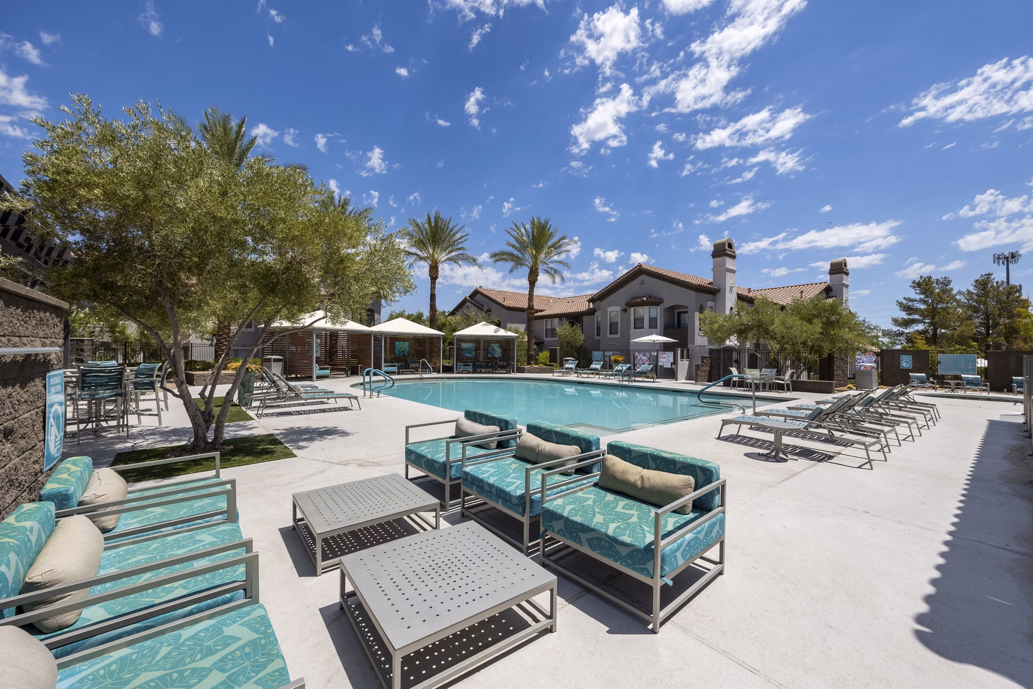 Luxurious poolside view at Cyan at Green Valley Apartments with modern lounge chairs and lush landscaping