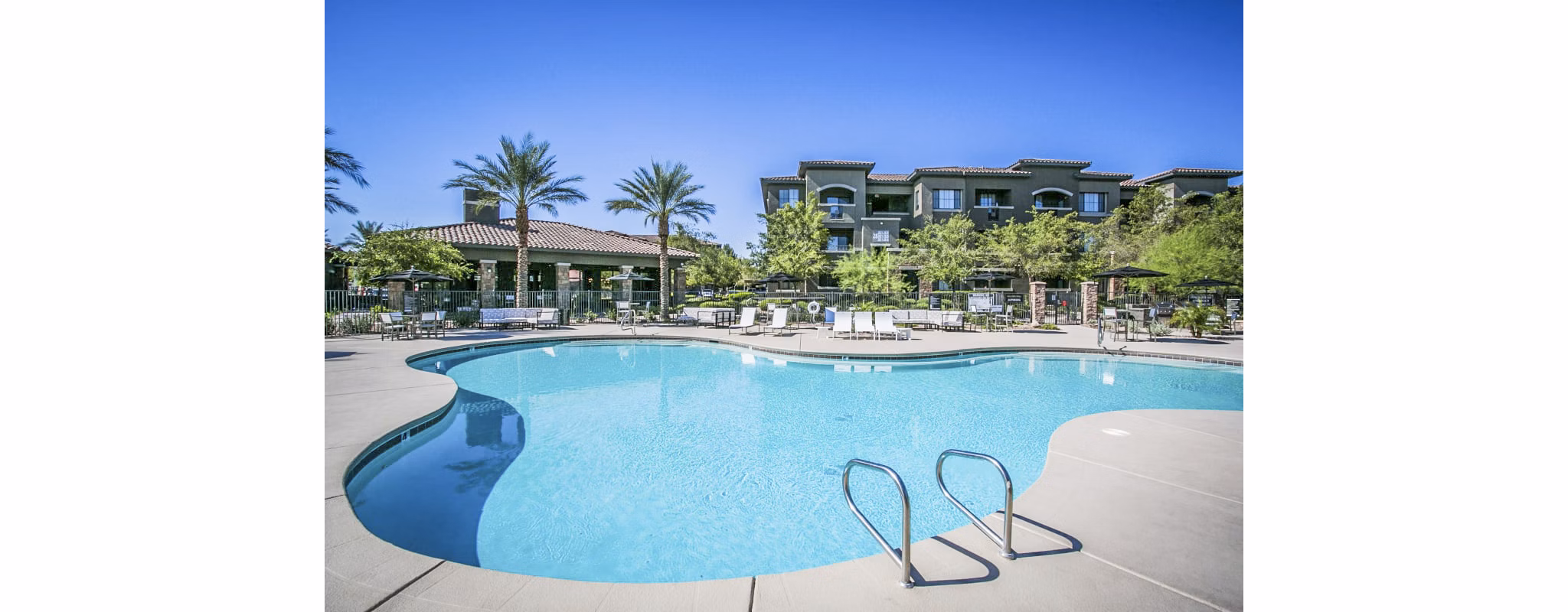 Pool surrounded by lounge chairs at The Presley luxury apartments in Whitney Ranch, offering resort-style relaxation for residents