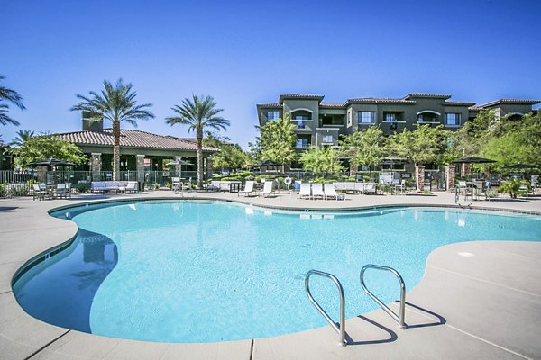 Pool surrounded by lounge chairs at The Presley luxury apartments in Whitney Ranch, offering resort-style relaxation for residents