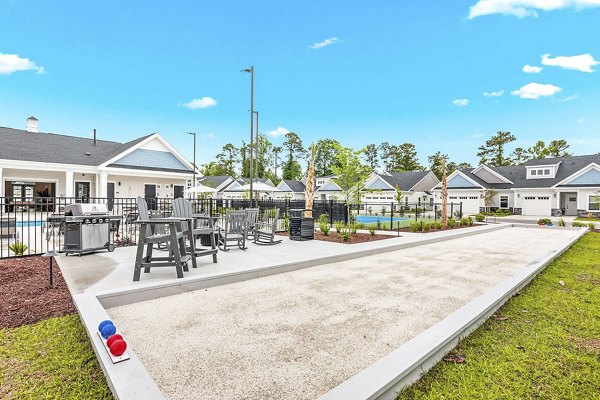 Recreational area with outdoor seating at River Rock at Blume Road Apartment Homes featuring green spaces and modern design