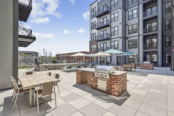 Outdoor grill area at The Navigator Apartments featuring modern BBQ stations and seating, ideal for social gatherings and leisure