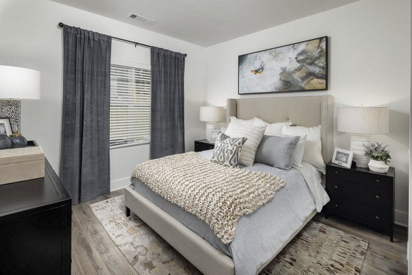 Cozy bedroom with neutral tones and modern furnishings at Prose Columbus Apartments, featuring a large window and stylish decor