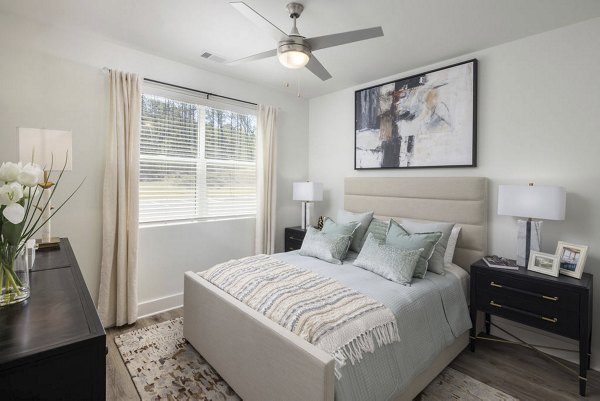 Cozy bedroom featuring modern furnishings and large windows at Bell's Lake Apartments