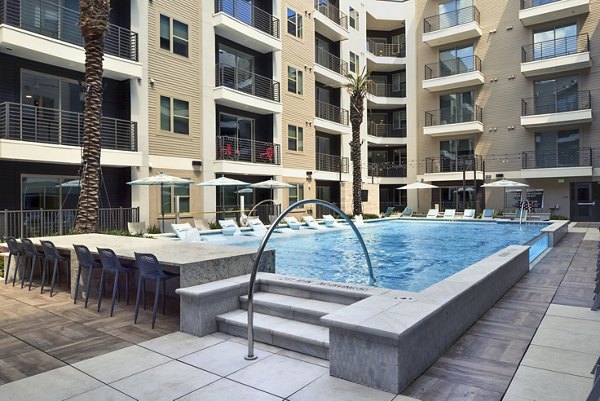 Luxurious pool area at Alta Washington Apartments featuring lounge chairs and cabanas