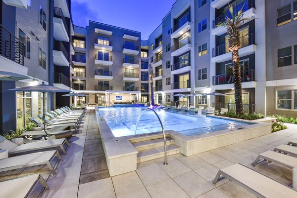Modern outdoor pool with lounge chairs at Alta Washington Apartments, offering a luxurious relaxation spot in the heart of the community