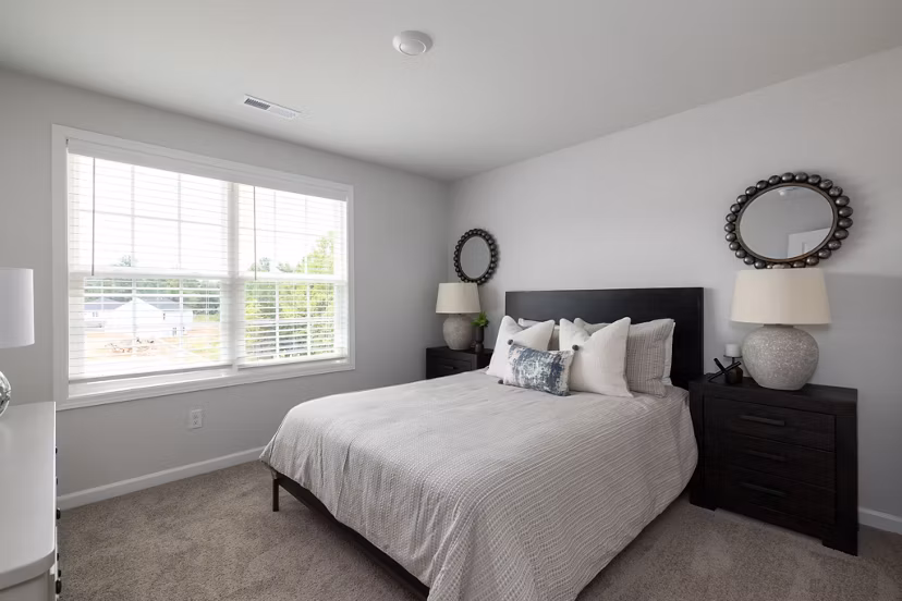 Cozy bedroom featuring modern furnishings at Smith Crossing Apartments with plush bedding and ample natural light