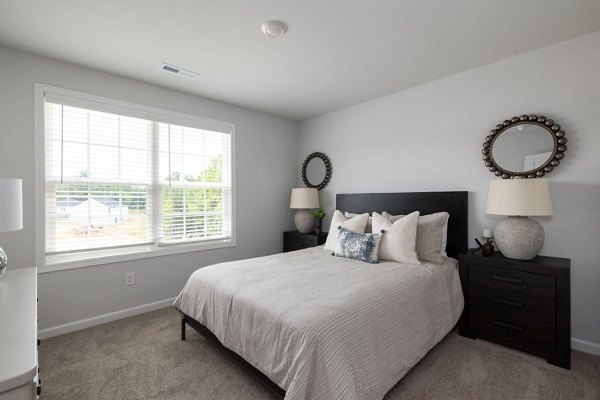 Cozy bedroom featuring modern furnishings at Smith Crossing Apartments with plush bedding and ample natural light