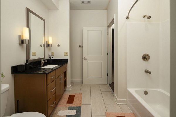 Modern bathroom featuring a spacious bathtub and stylish vanity with mirror and lights in luxury apartments