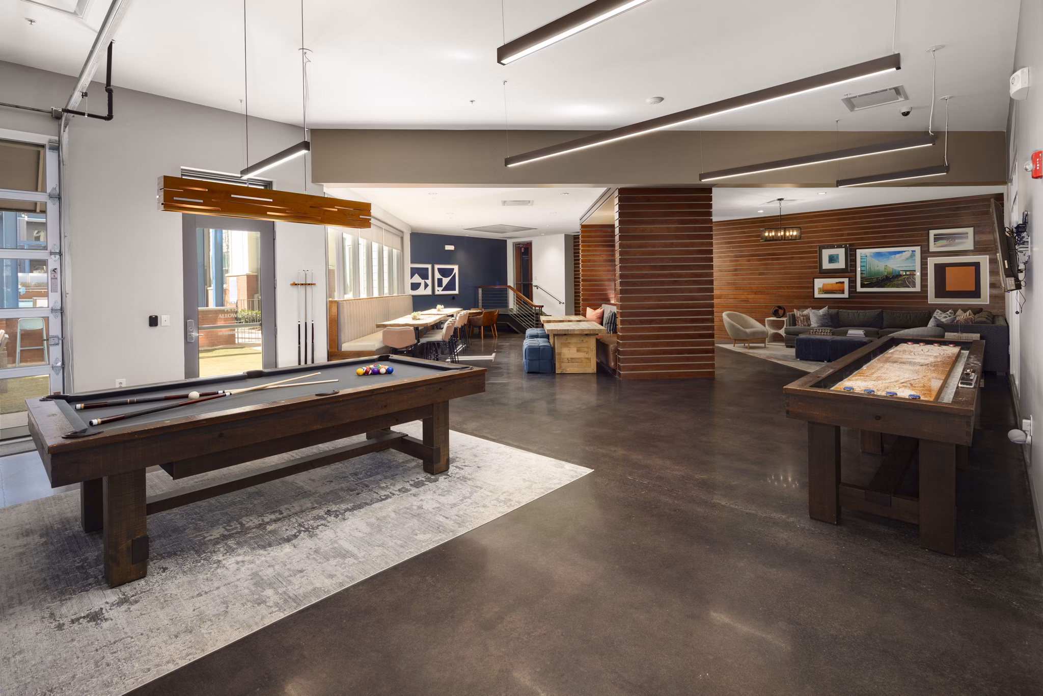 Recreational room with a pool table and shuffleboard in luxury apartments featuring modern seating and colorful wall art