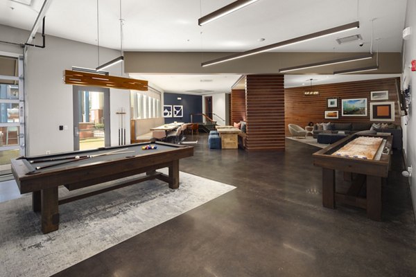 Recreational room with a pool table and shuffleboard in luxury apartments featuring modern seating and colorful wall art