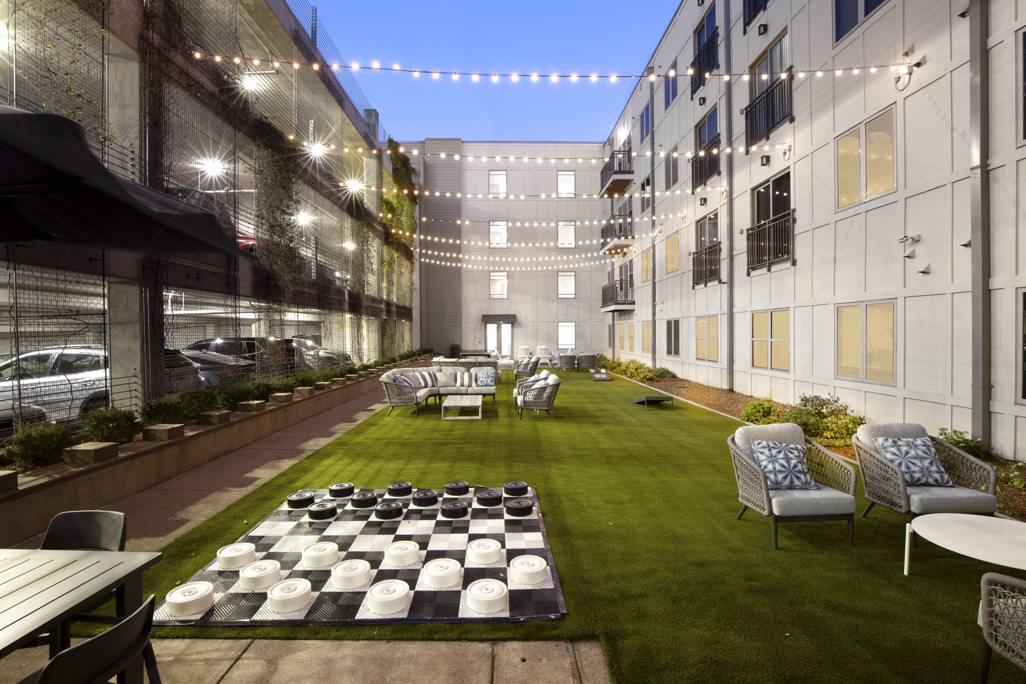 Outdoor courtyard with artificial grass, string lights, and seating for socializing at luxury apartments