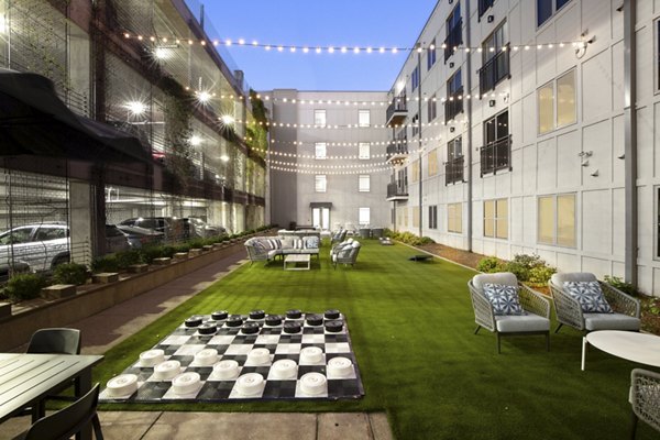 Outdoor courtyard with artificial grass, string lights, and seating for socializing at luxury apartments