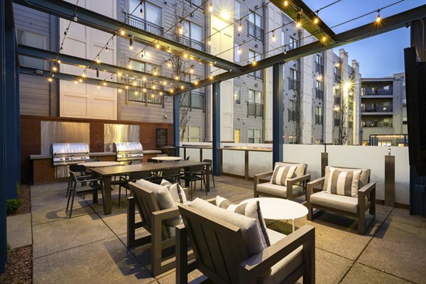 Outdoor patio with string lights, seating, tables, and grills at luxury apartments