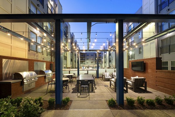 Outdoor patio area with string lights, tables, and grills at luxury apartments