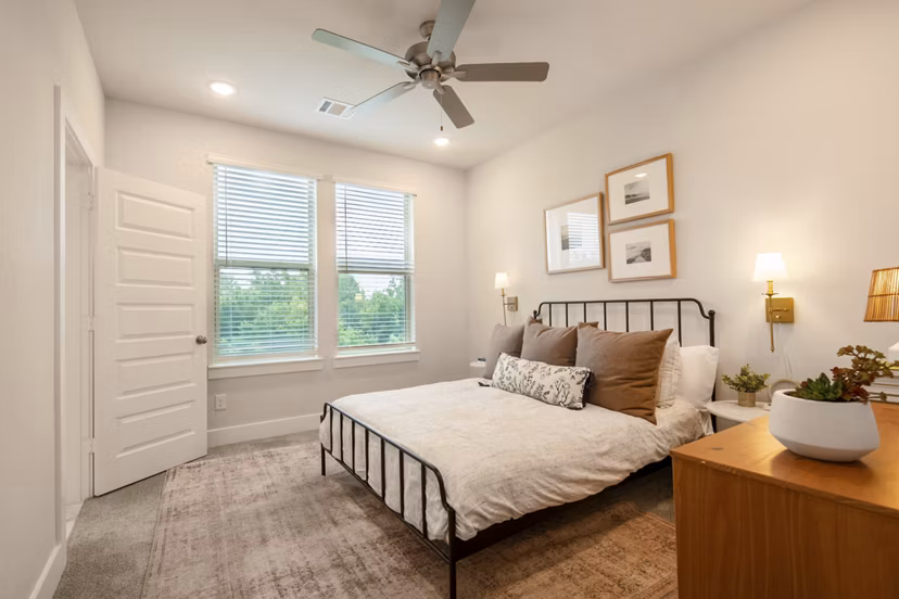Cozy bedroom with modern decor in Mission at Johnson Creek Apartments, featuring ample natural light for a relaxing ambiance