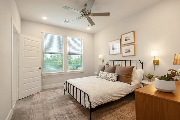 Cozy bedroom with modern decor in Mission at Johnson Creek Apartments, featuring ample natural light for a relaxing ambiance