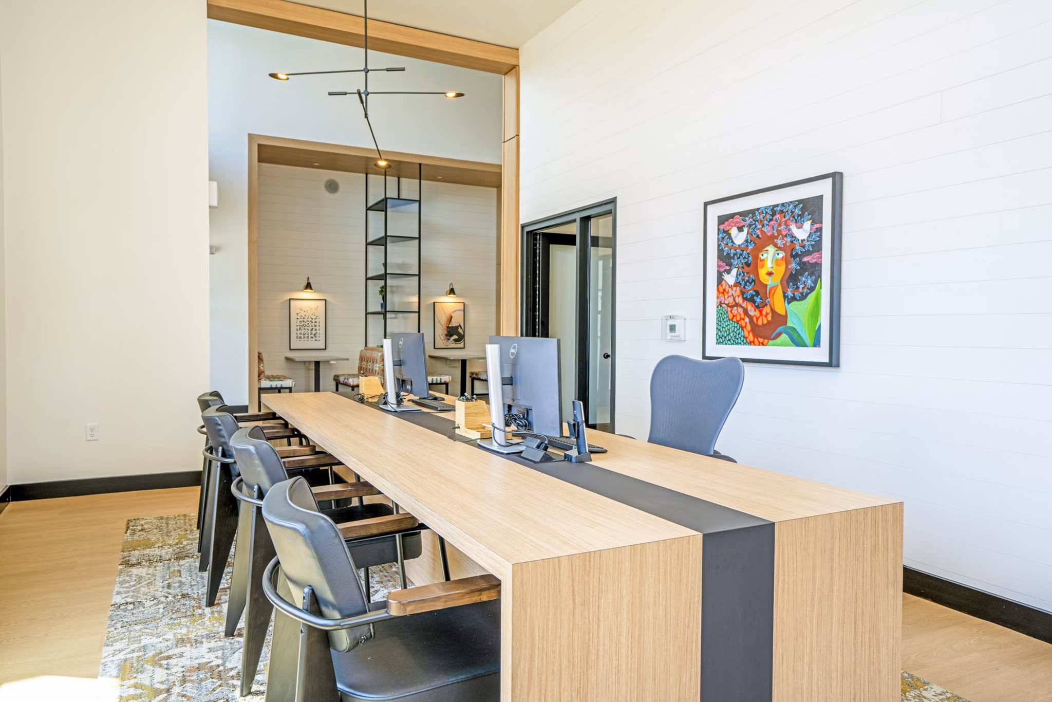 Lariat Apartments: Modern clubhouse business center with sleek workstations and natural lighting