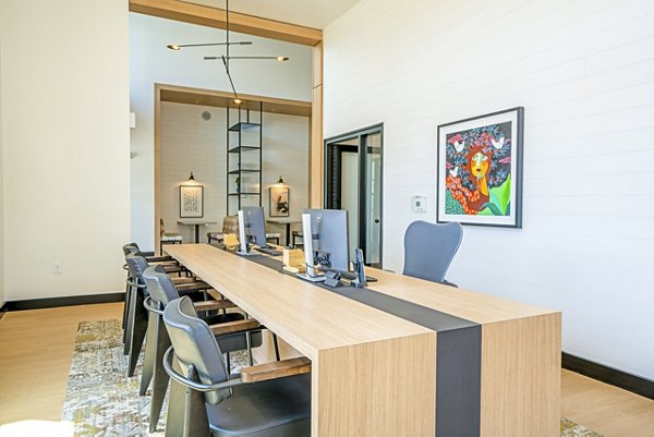 Lariat Apartments: Modern clubhouse business center with sleek workstations and natural lighting