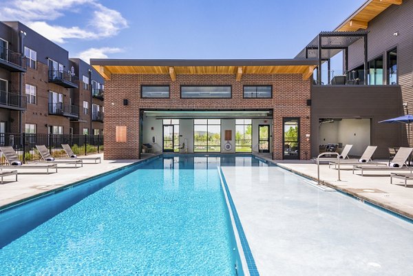 Pool area with lounge chairs and umbrellas at Railway Flats Apartments, offering luxury amenities for relaxation and leisure