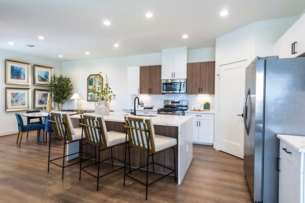 Modern kitchen featuring stainless steel appliances and granite countertops in Eden at Sunterra Apartments