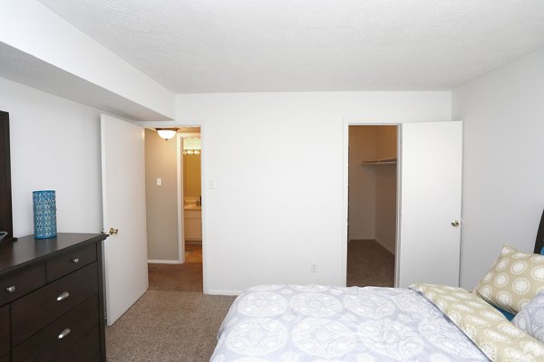 Cozy bedroom with modern decor at The M Club Apartments featuring plush bedding and ample natural light