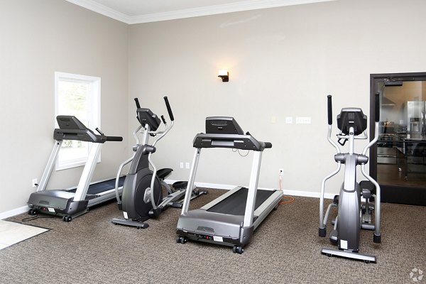 Fully-equipped fitness center with modern machines at The M Club Apartments, offering a dynamic workout experience for residents