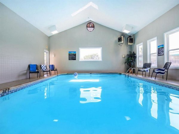 Outdoor swimming pool with sun loungers and palm trees at The M Club Apartments, offering luxurious leisure amenities