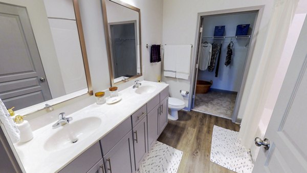 Modern bathroom with sleek fixtures and large mirror in Indigo at Cross Creek Apartments