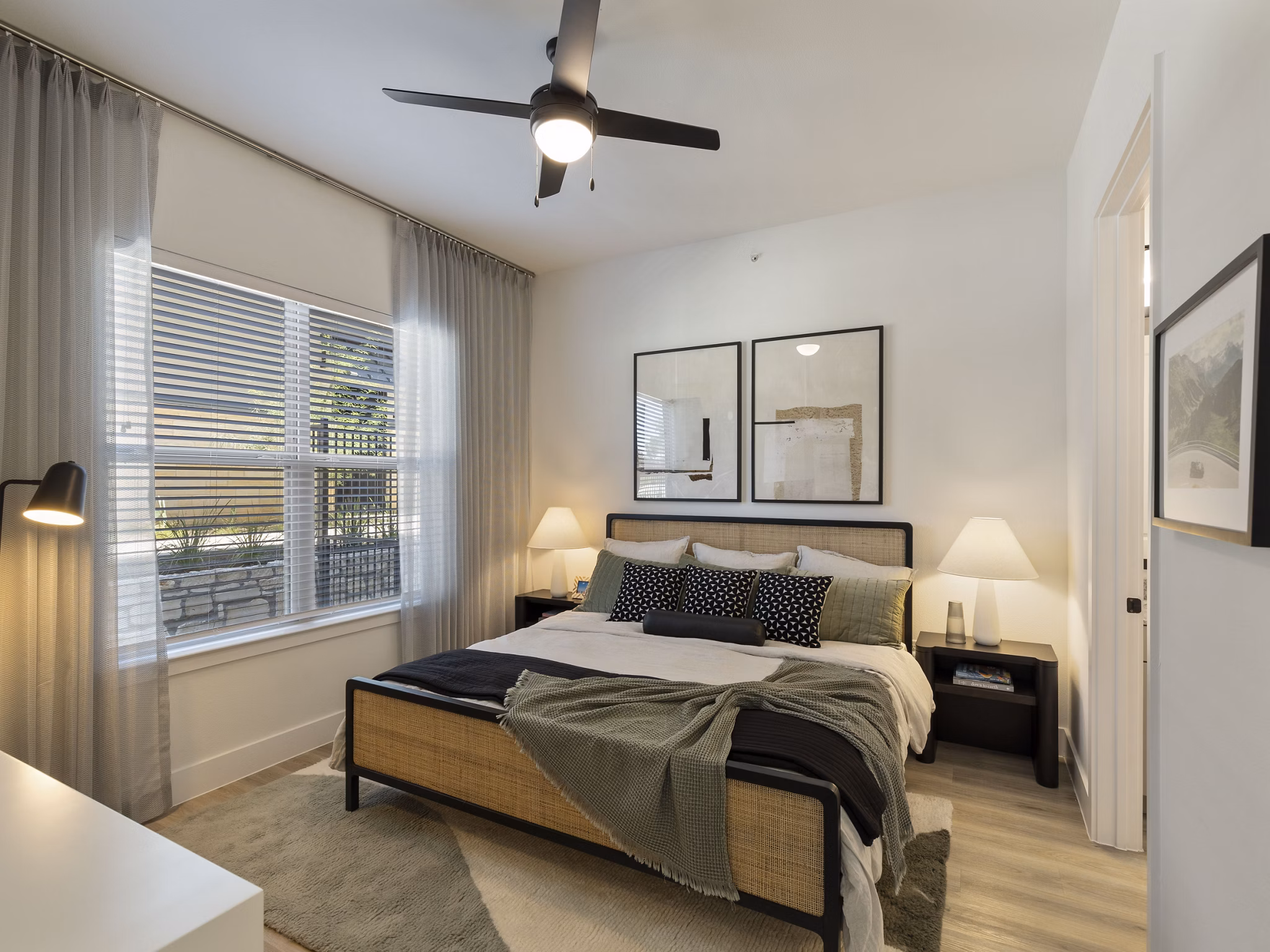 Bedroom with plush carpeting and ceiling fan in The Evergrove at Crystal Village Apartments, offering luxury living in a serene setting