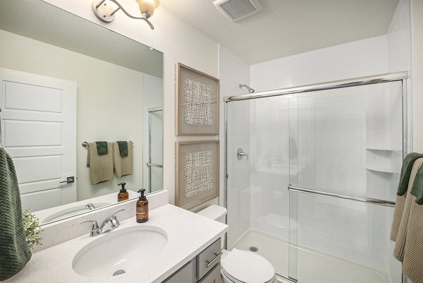 Bathroom featuring sleek fixtures and marble countertops at The Cottages at Erie Commons Apartments, luxury living by Greystar