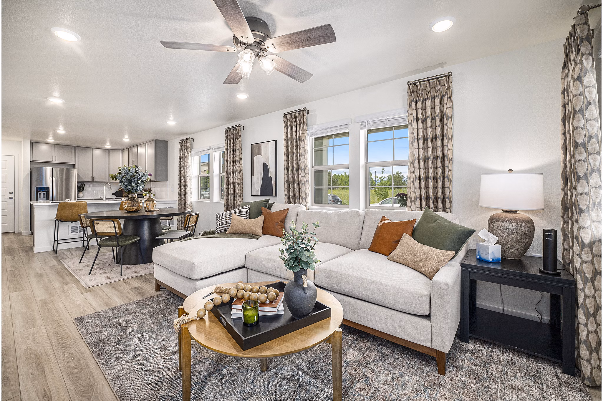 Cozy living room with large windows and modern furnishings at The Cottages at Erie Commons Apartments