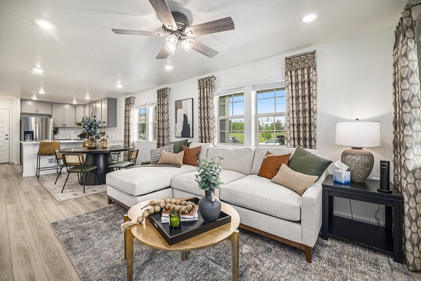 Cozy living room with large windows and modern furnishings at The Cottages at Erie Commons Apartments