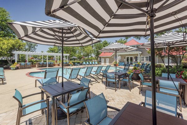 Poolside relaxation area at Arbor Steele Creek Apartments featuring luxurious sun loungers and lush landscaping