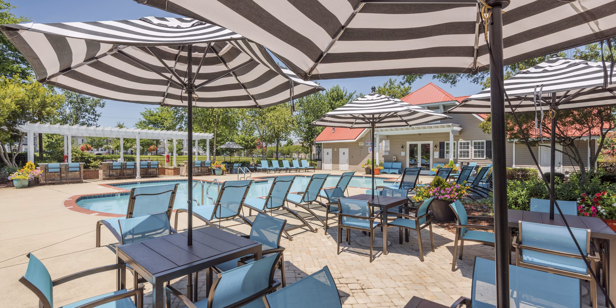Resort-style blue-tiled pool with lush landscaping at Arbor Steele Creek Apartments, offering luxury living in Charlotte