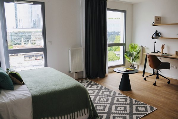 Bedroom with large windows, a study desk, and a city view.