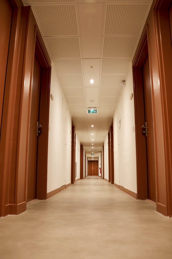 Long hallway with multiple doors and ceiling lights.