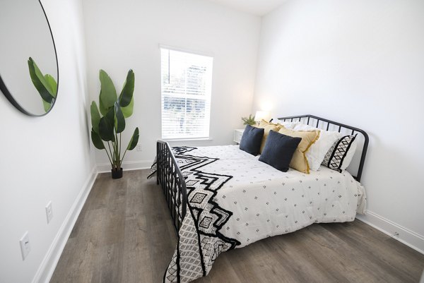 Cozy bedroom featuring modern furnishings at Reve on the Creek Apartments