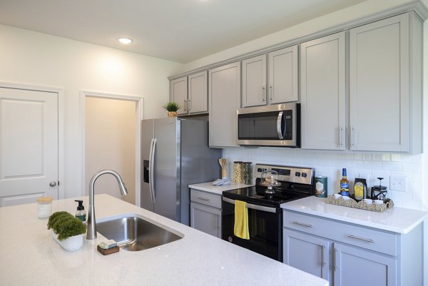 Modern kitchen with stainless appliances and granite countertops in Reve on the Creek Apartments